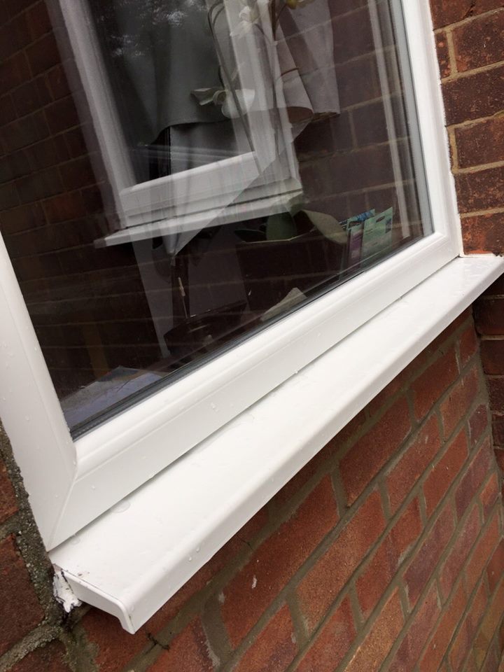 Close-up of a clean white window frame and sill on a brick property