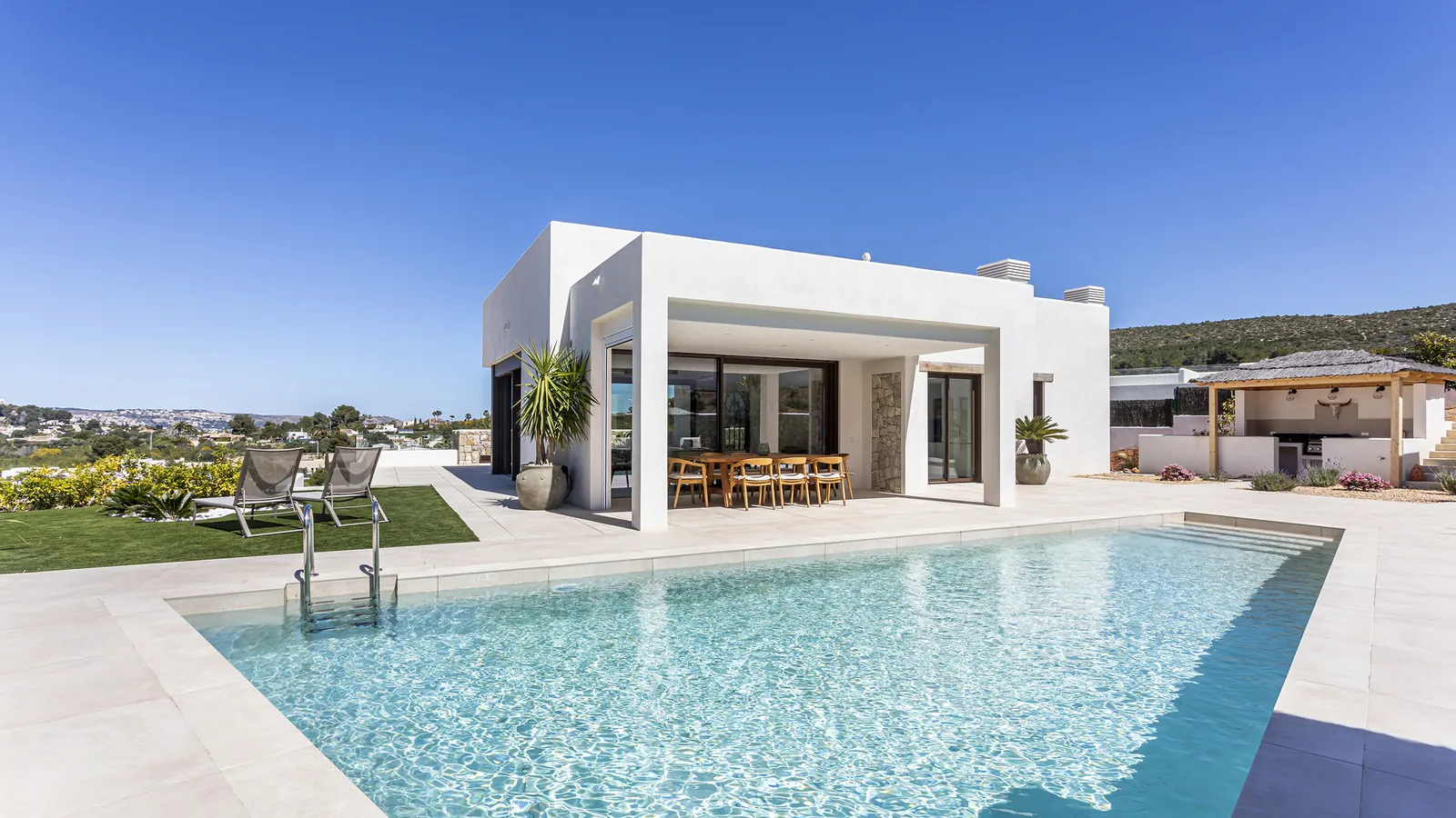 Casa Turna en Jávea: villa blanca de nueva construcción con piscina y jardín bajo cielo despejado