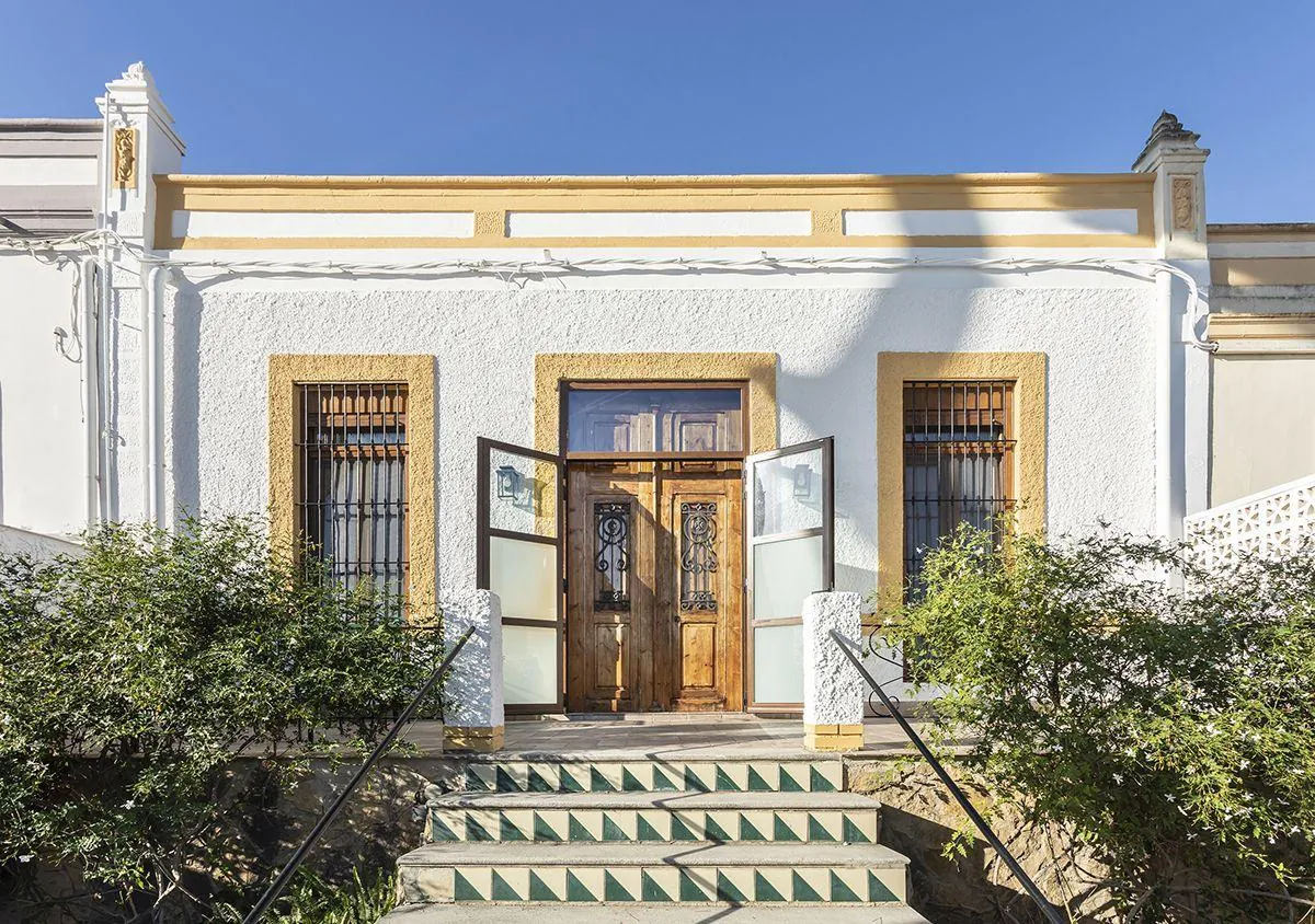 Fachada de la casa de pueblo de 1922 en Godella, con zócalo de piedra y carpinterías de madera