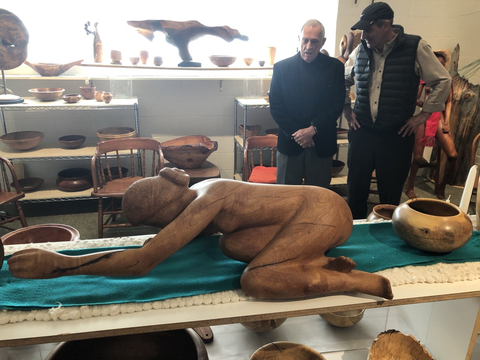 A studio gathering with a wood figure and vessels on display