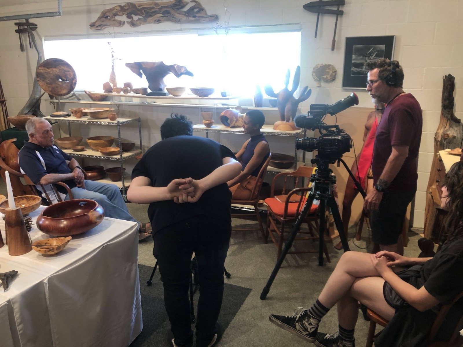People gathered among wood sculptures and vessels in the studio