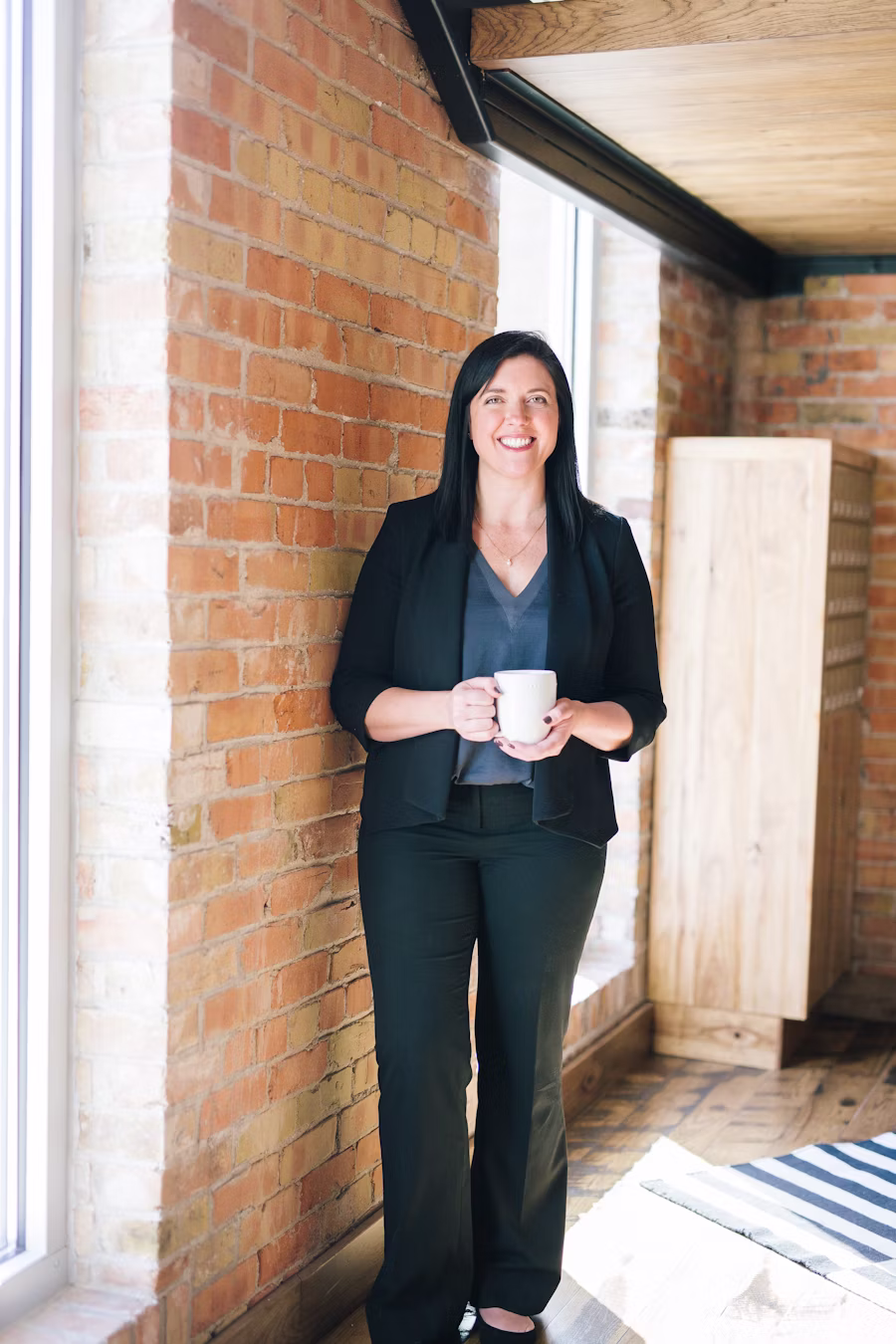 A coach standing relaxed with a coffee, away from a screen