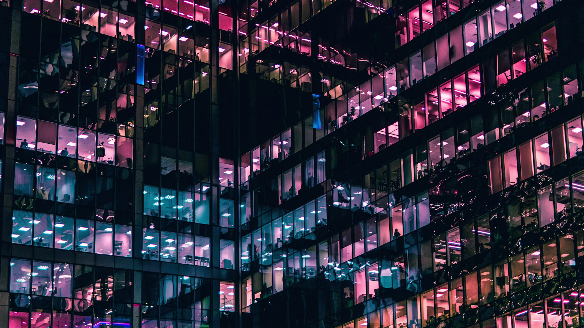 A modern building lit at night with people working inside