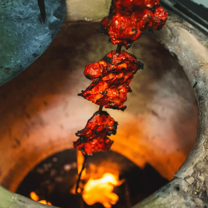 Tandoor oven with skewers over flame