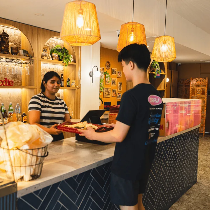 Staff serving a customer at the herringbone-tile counter