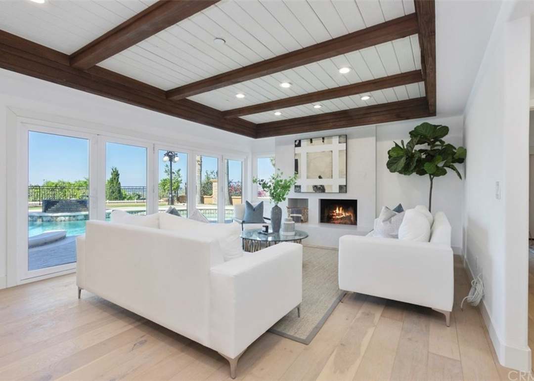 Sunlit living room with beamed ceiling and pool view in a Nellie Gail Ranch estate
