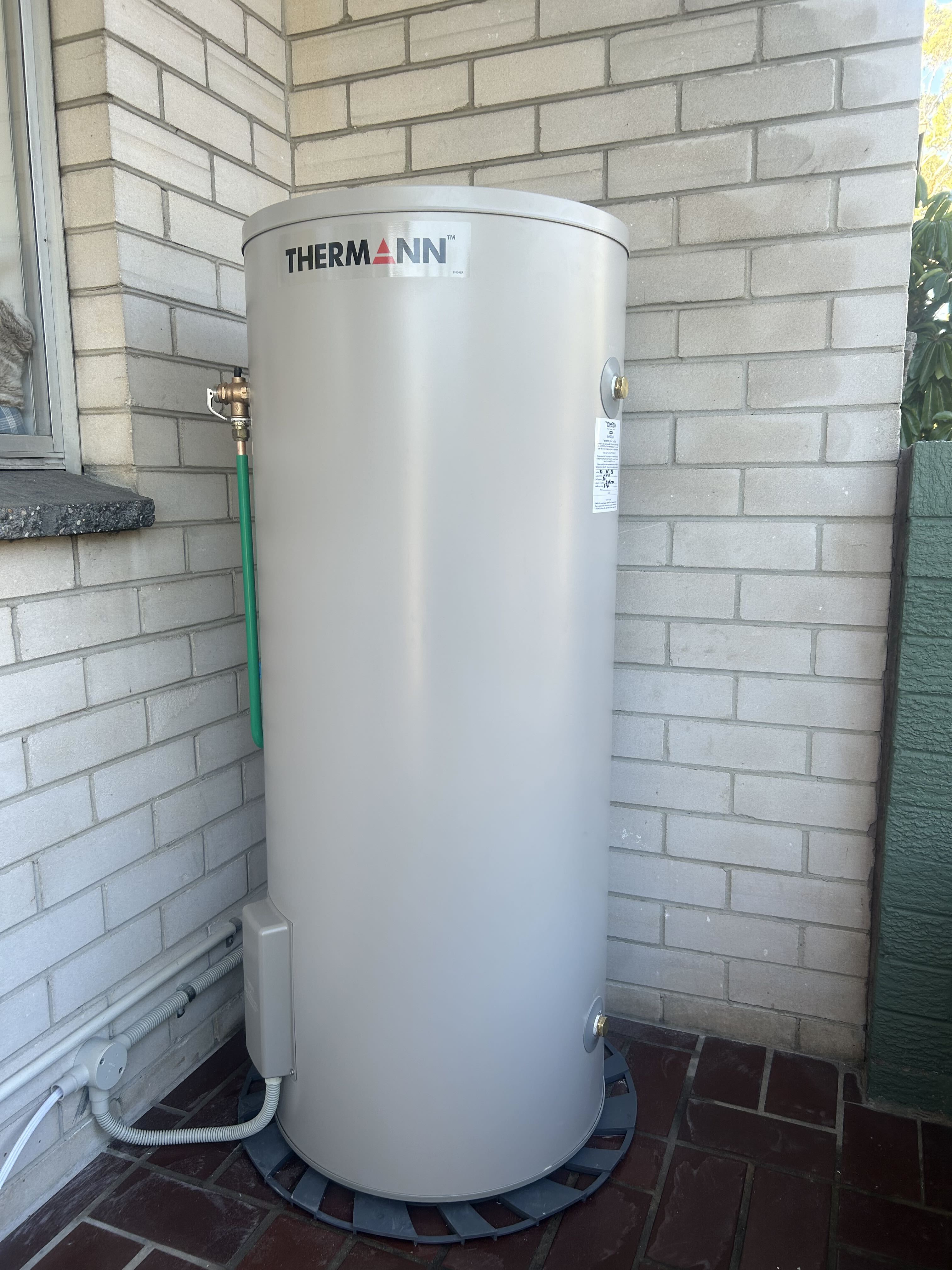 Thermann storage hot water unit beside brick wall