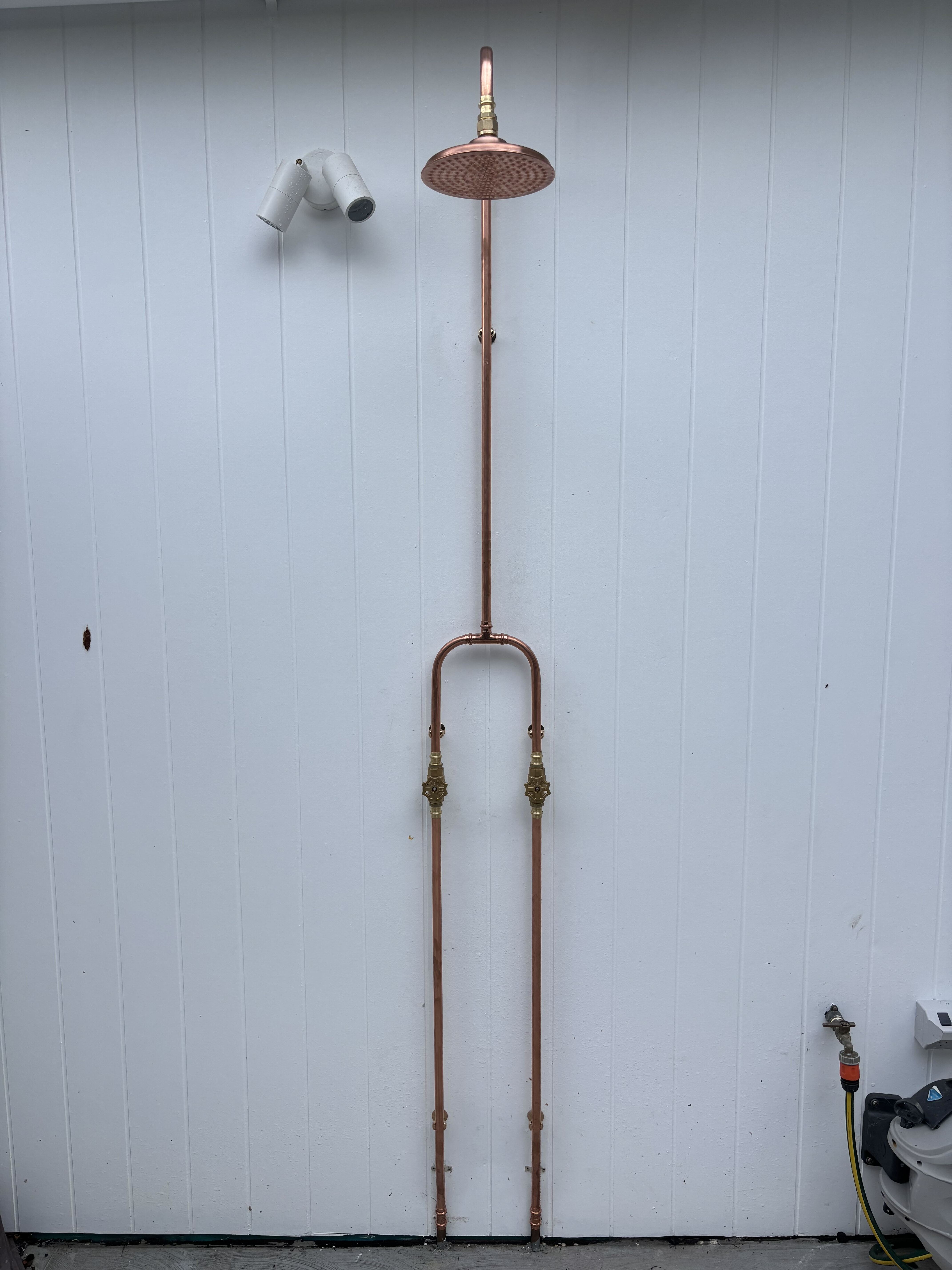 Copper outdoor shower on white wall