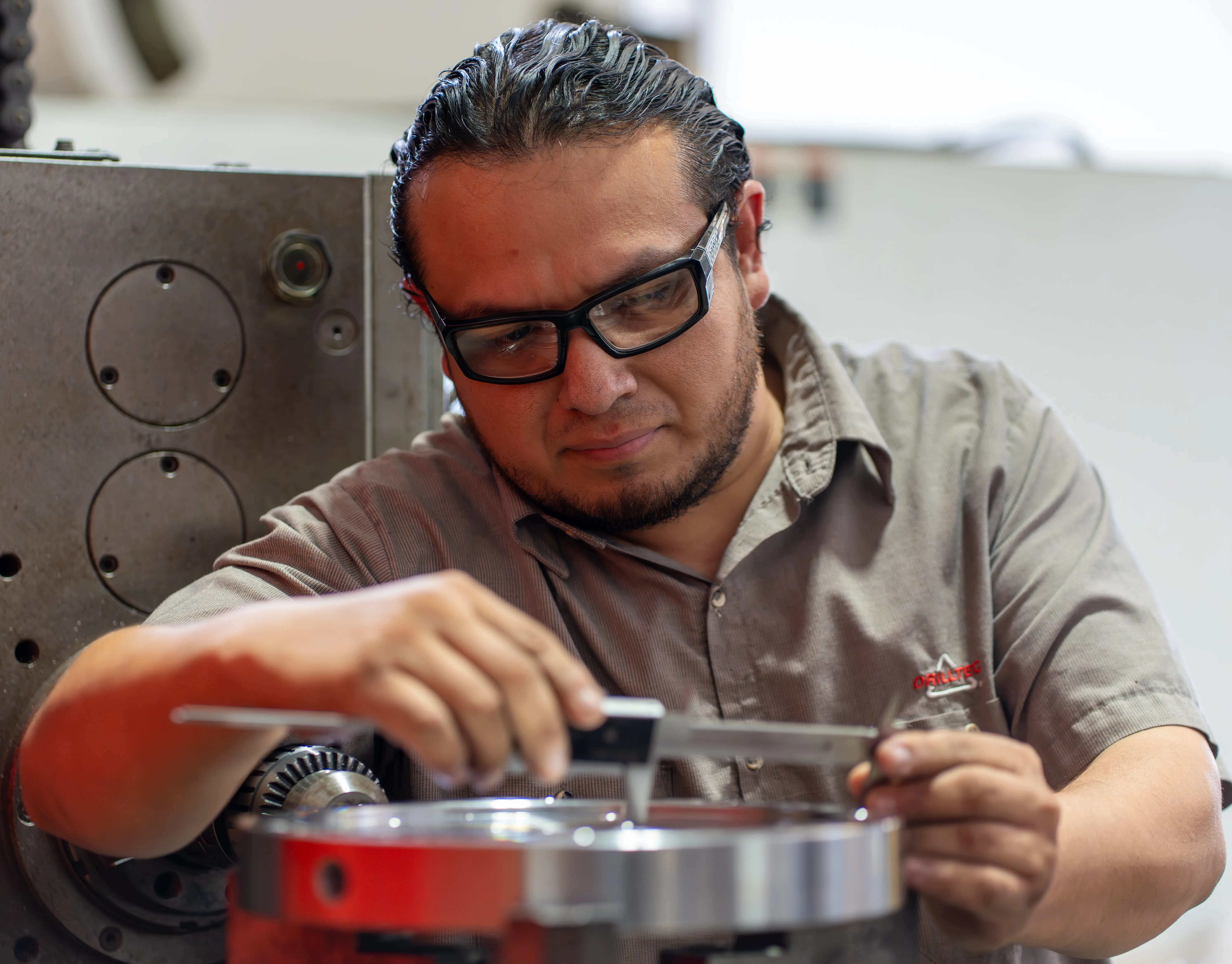 Drilltec technician using precision measurement tools — industrial photography