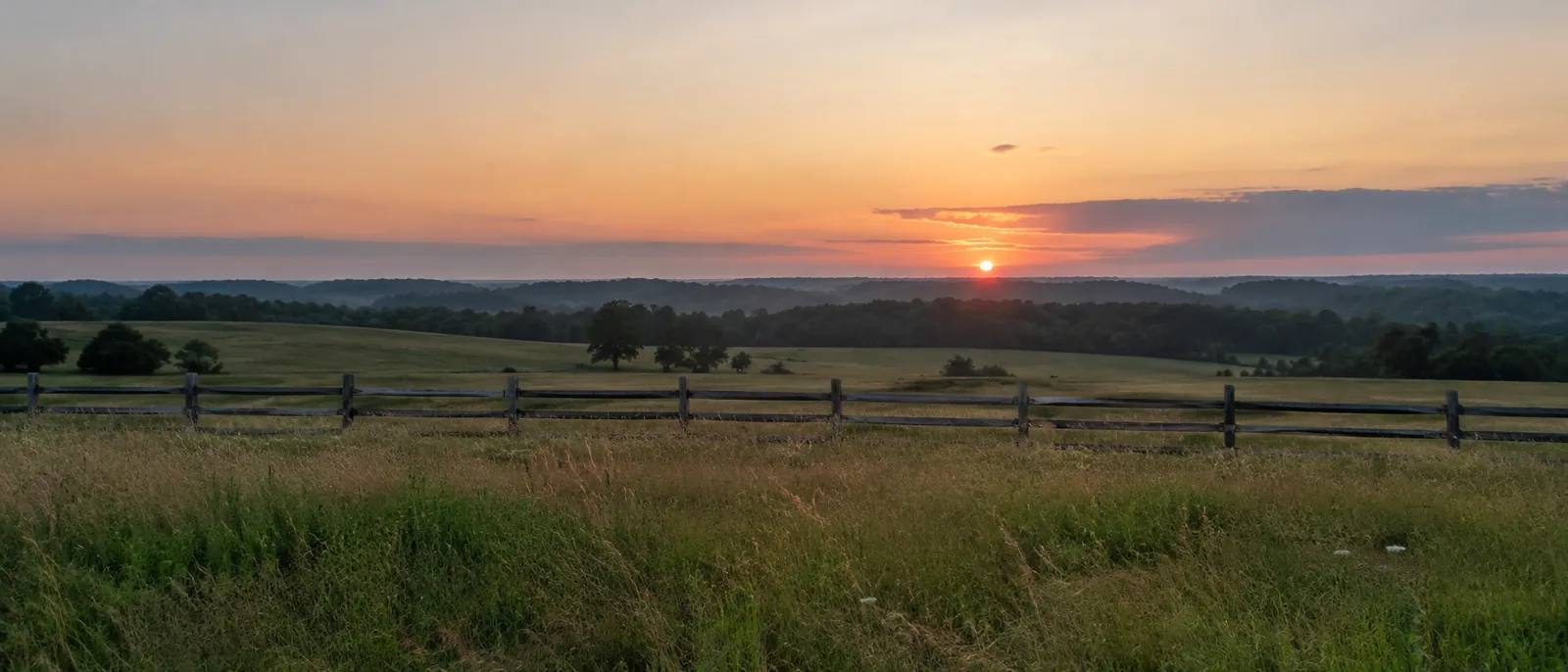 Open farmland and a split-rail fence at dusk