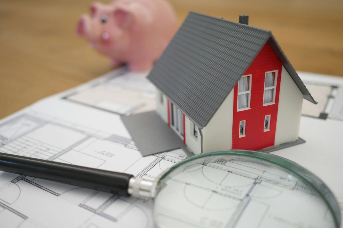 A magnifying glass beside a model house A magnifying glass beside a model house