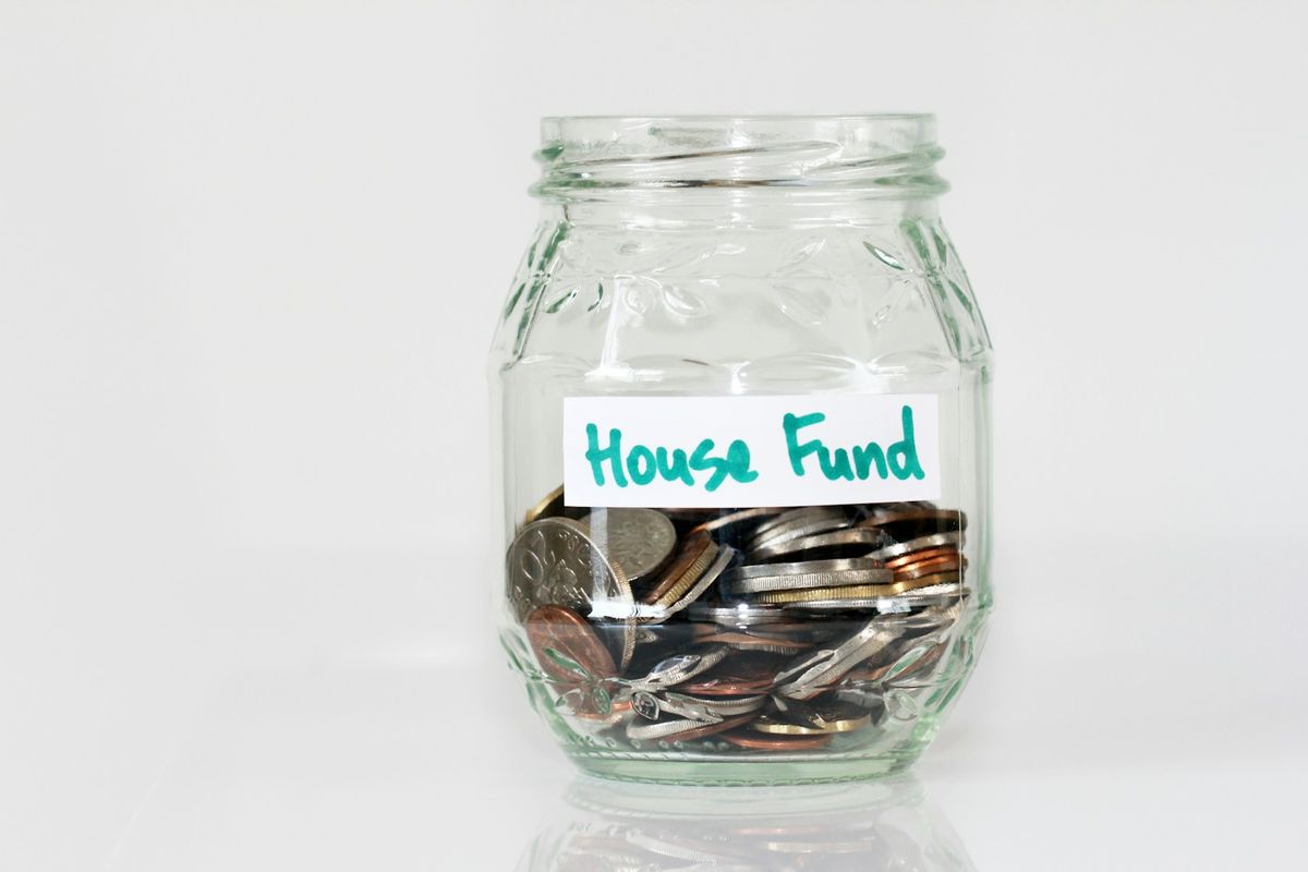 A jar of coins labeled House Fund A jar of coins labeled House Fund