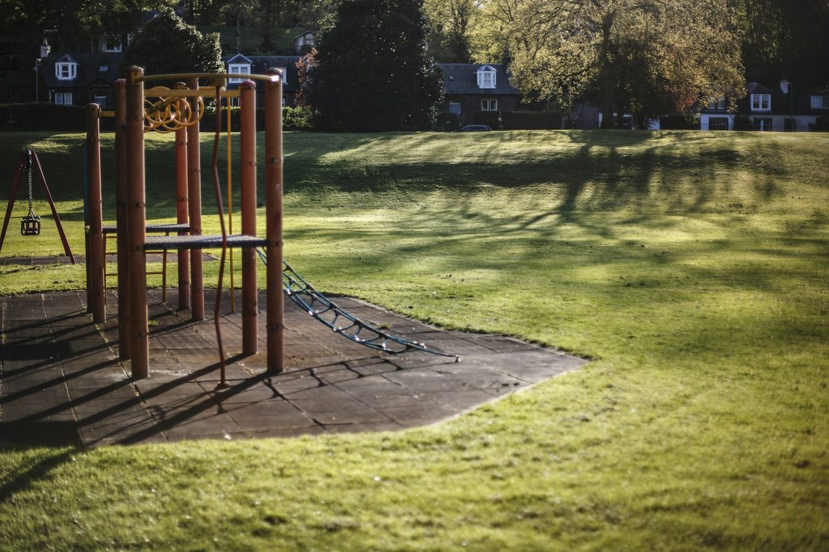 An empty neighborhood playground on a grassy lawn