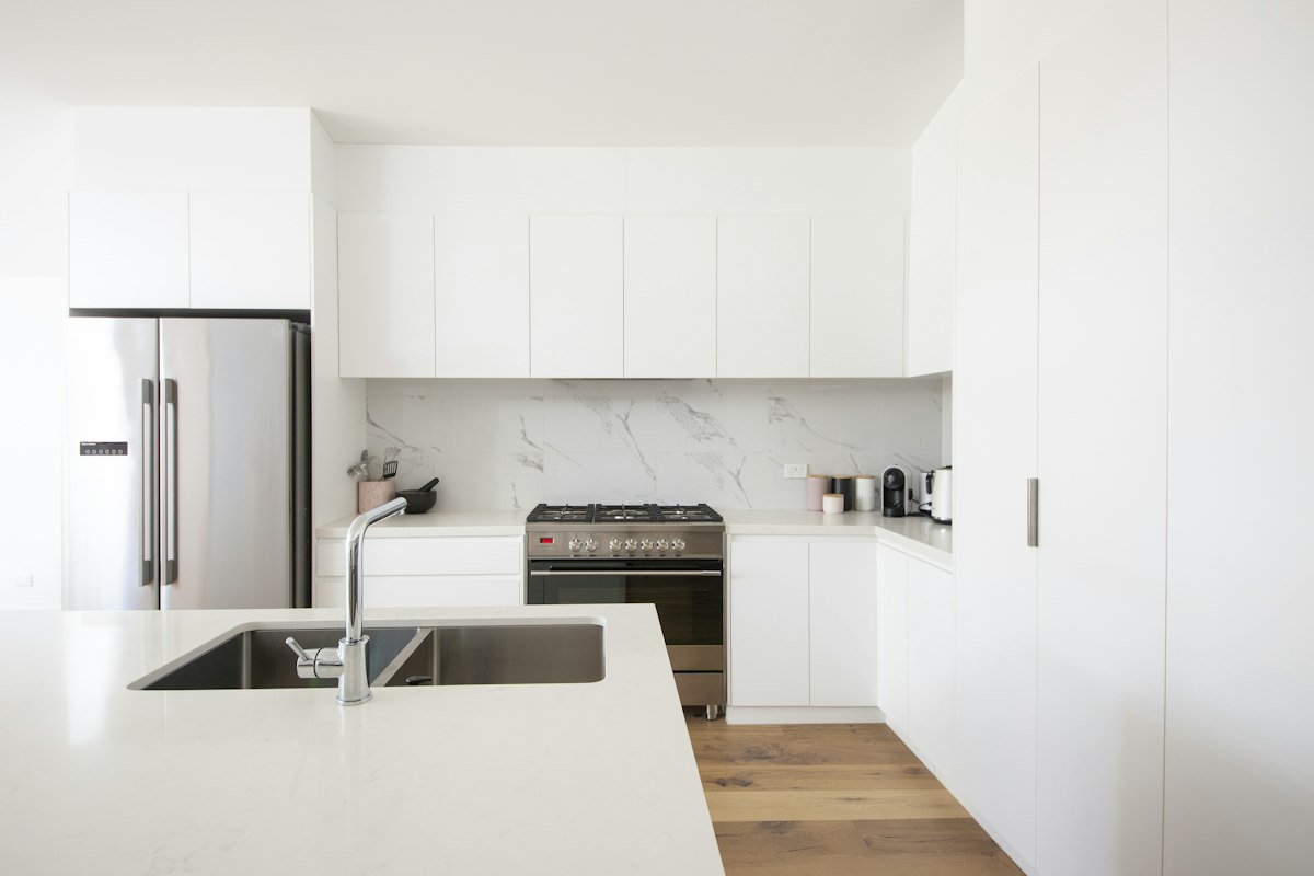 A clean white kitchen with an island and stainless appliances