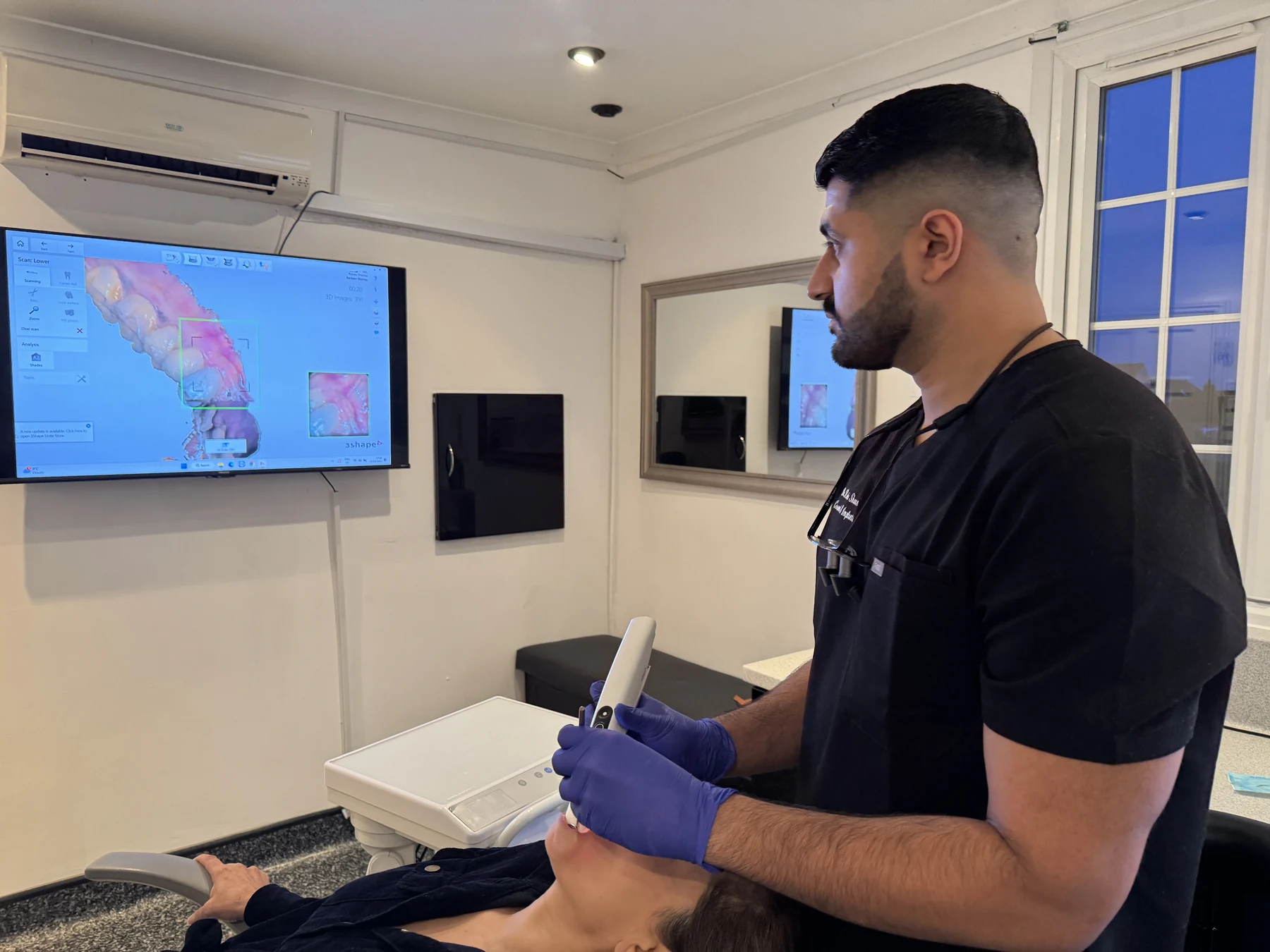 Dr Raheis Sharma taking a 3D digital scan of a patient's teeth at Spry Smiles, Billericay, with the scan displayed on screen