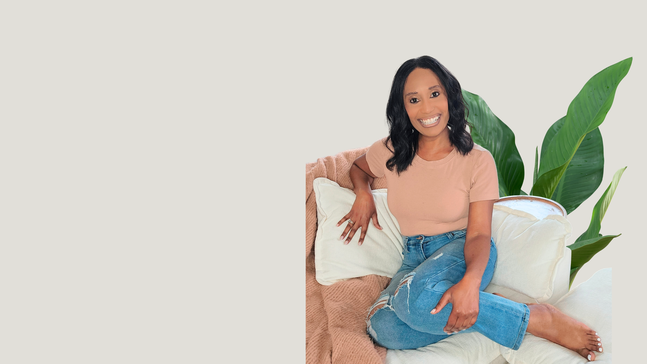 Ashley Binns smiling, seated on a couch beside a plant
