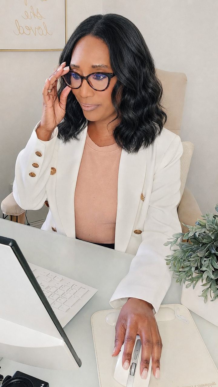 Ashley Binns in a white blazer, working at her desk