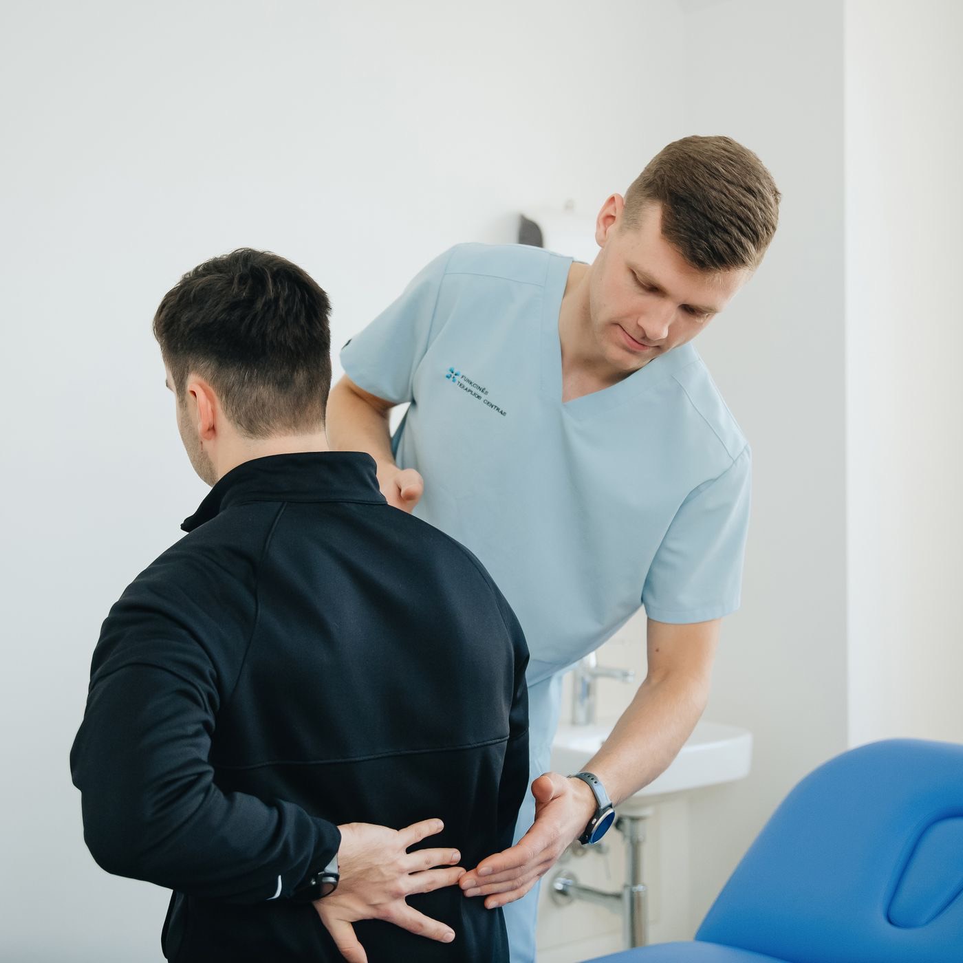Physiotherapist assessing a patient's lower back