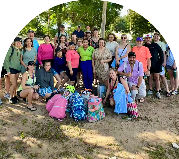  Large group of people posing outdoors on a sunny day with colorful backpacks and casual clothing in a natural setting