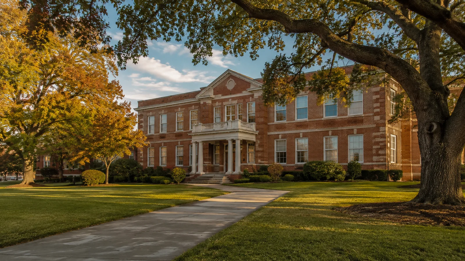 Established red-brick Texas school building framed by mature autumn oak trees