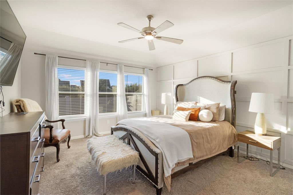 Primary bedroom with ceiling fan, dresser, and mounted TV