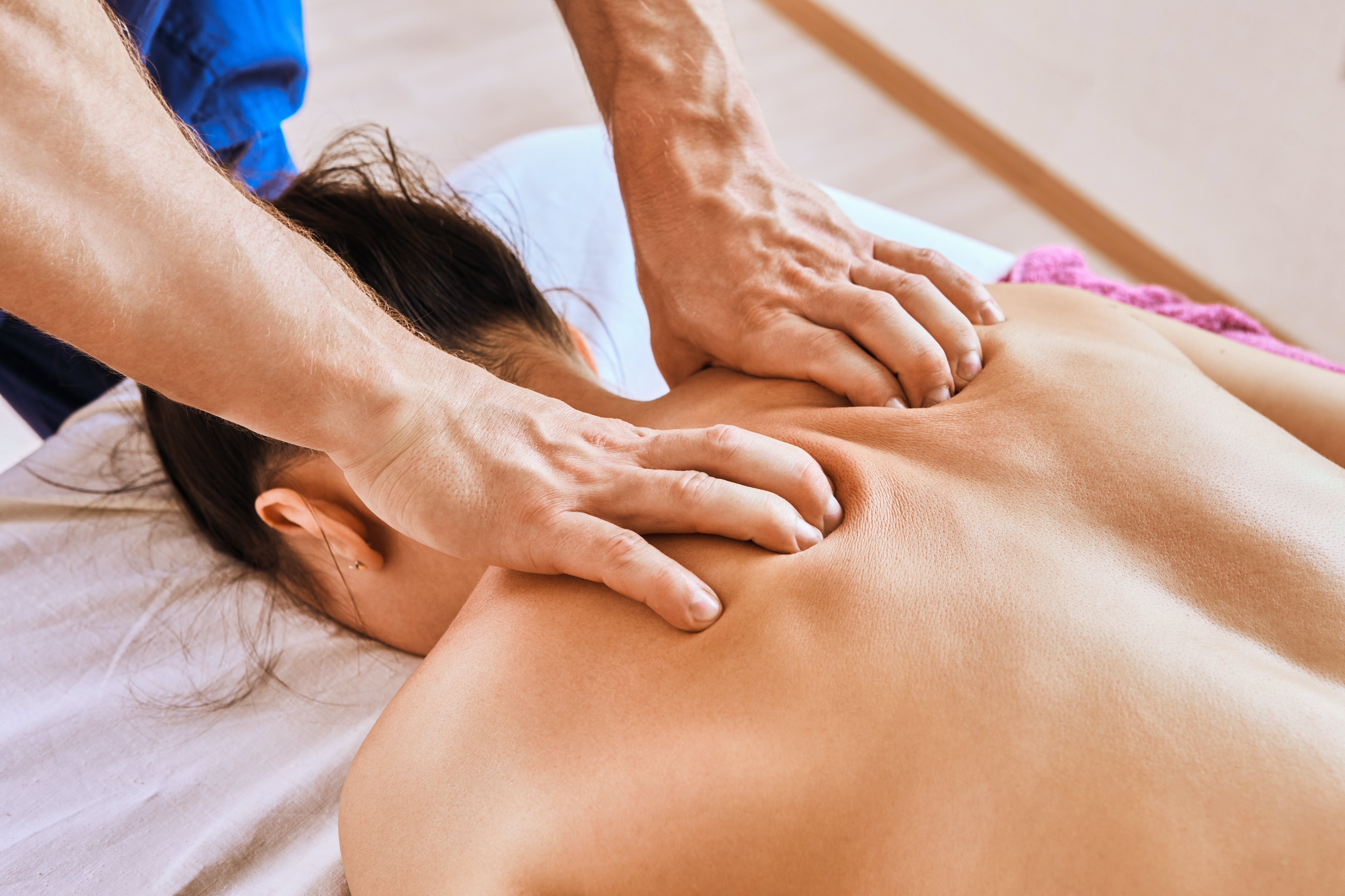 Licensed massage therapist performing deep tissue back massage in Regina clinic.