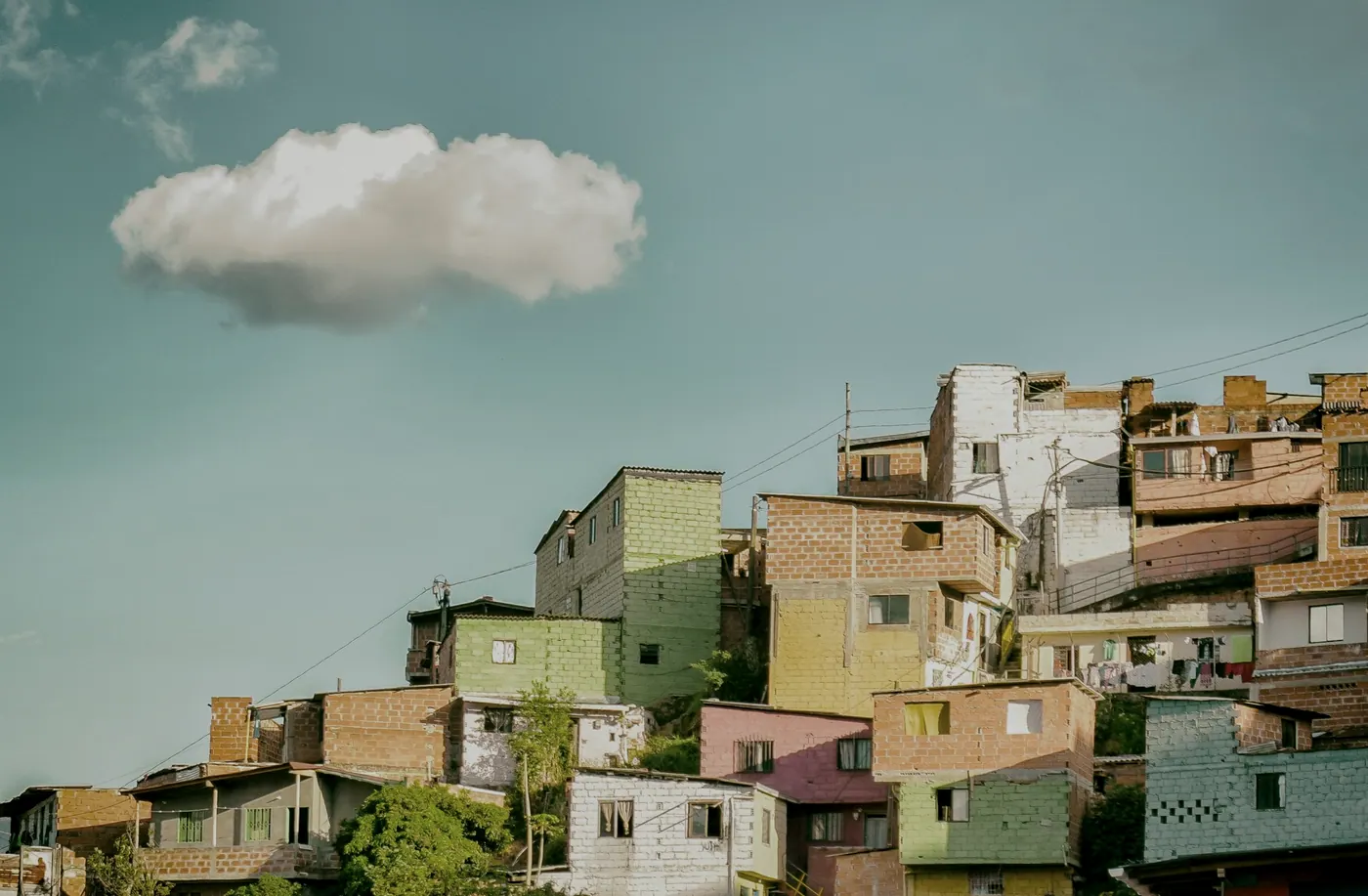 Casas de colores apiladas en una ladera de Medellín bajo un cielo despejado.