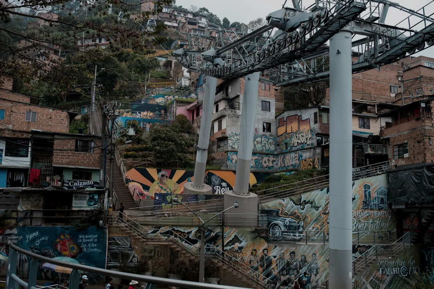 Cabinas del metrocable pasando sobre las casas de la ladera, con graffiti en los muros.