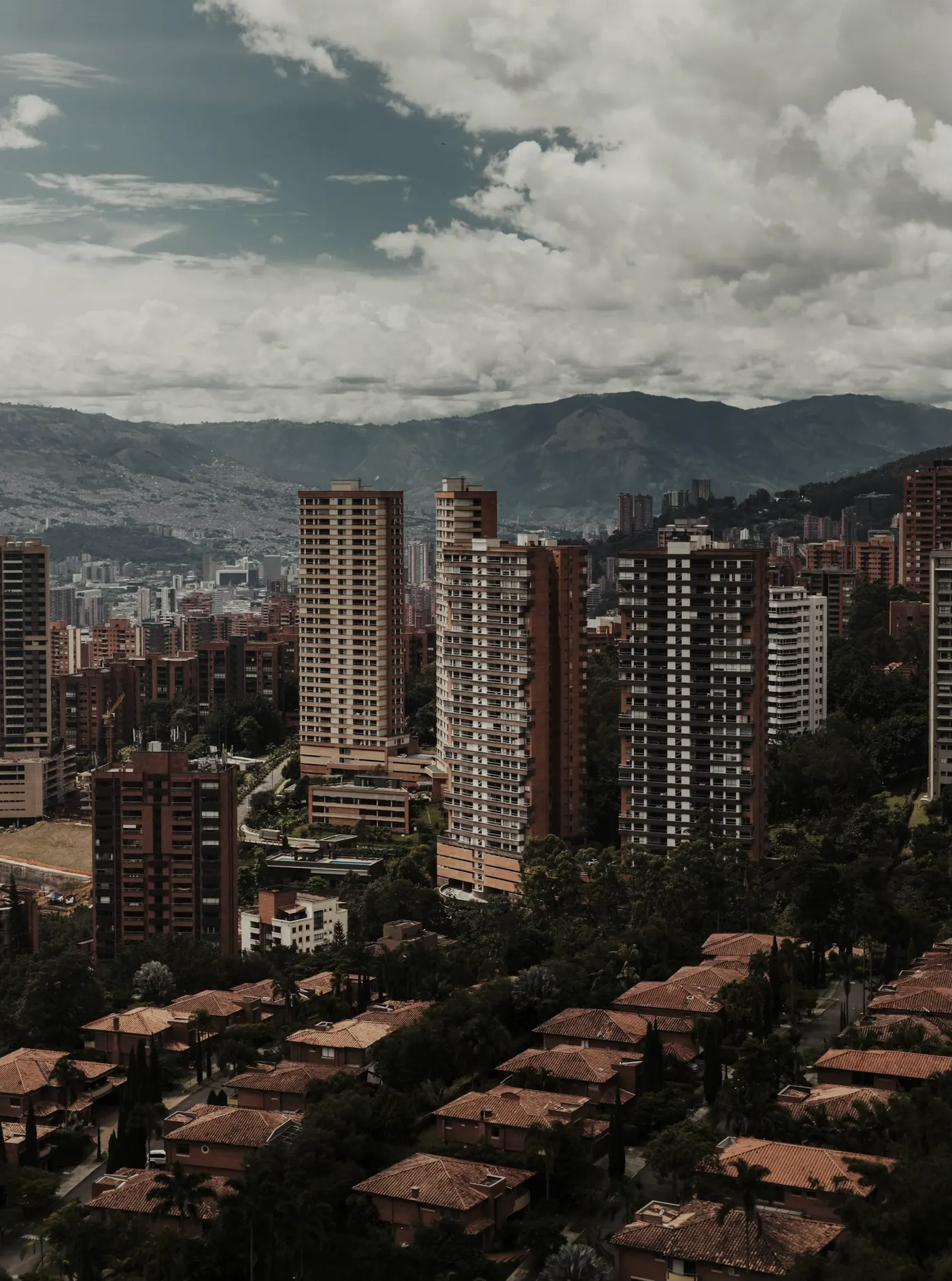 Torres de ladrillo de Medellín con la montaña y nubes bajas detrás.