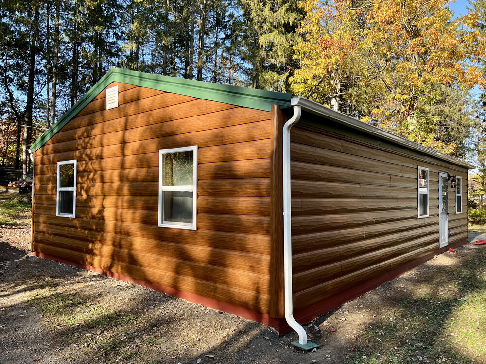 Log-look cabin with green standing-seam metal roofline and new gutters