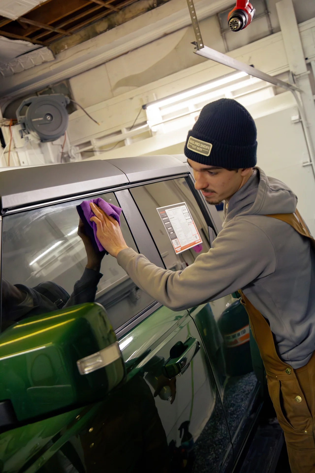 Technician cleaning a truck window before installing tint
