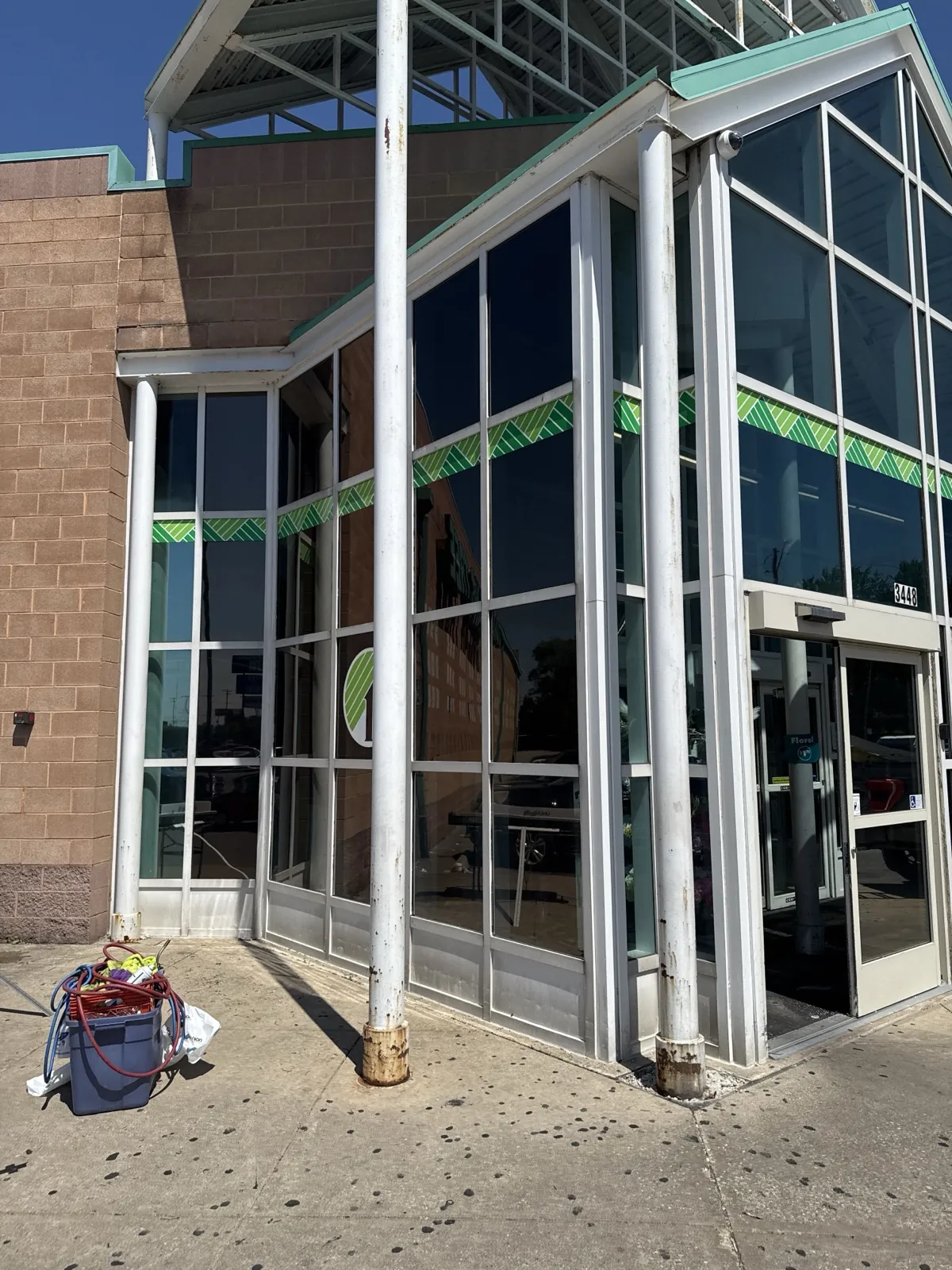 Glass-front commercial building with window film installation gear outside