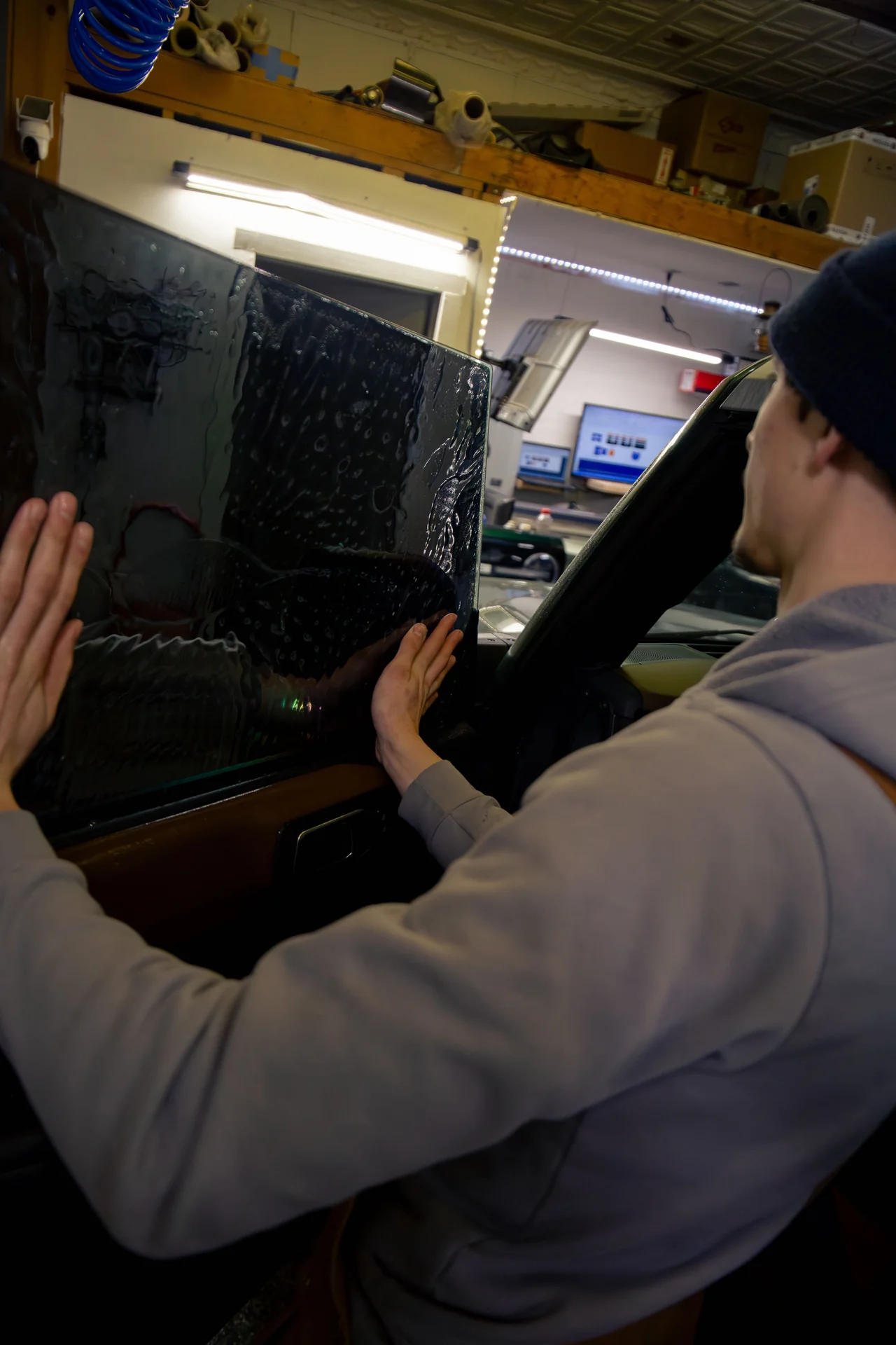Technician applying window tint film to a car door window