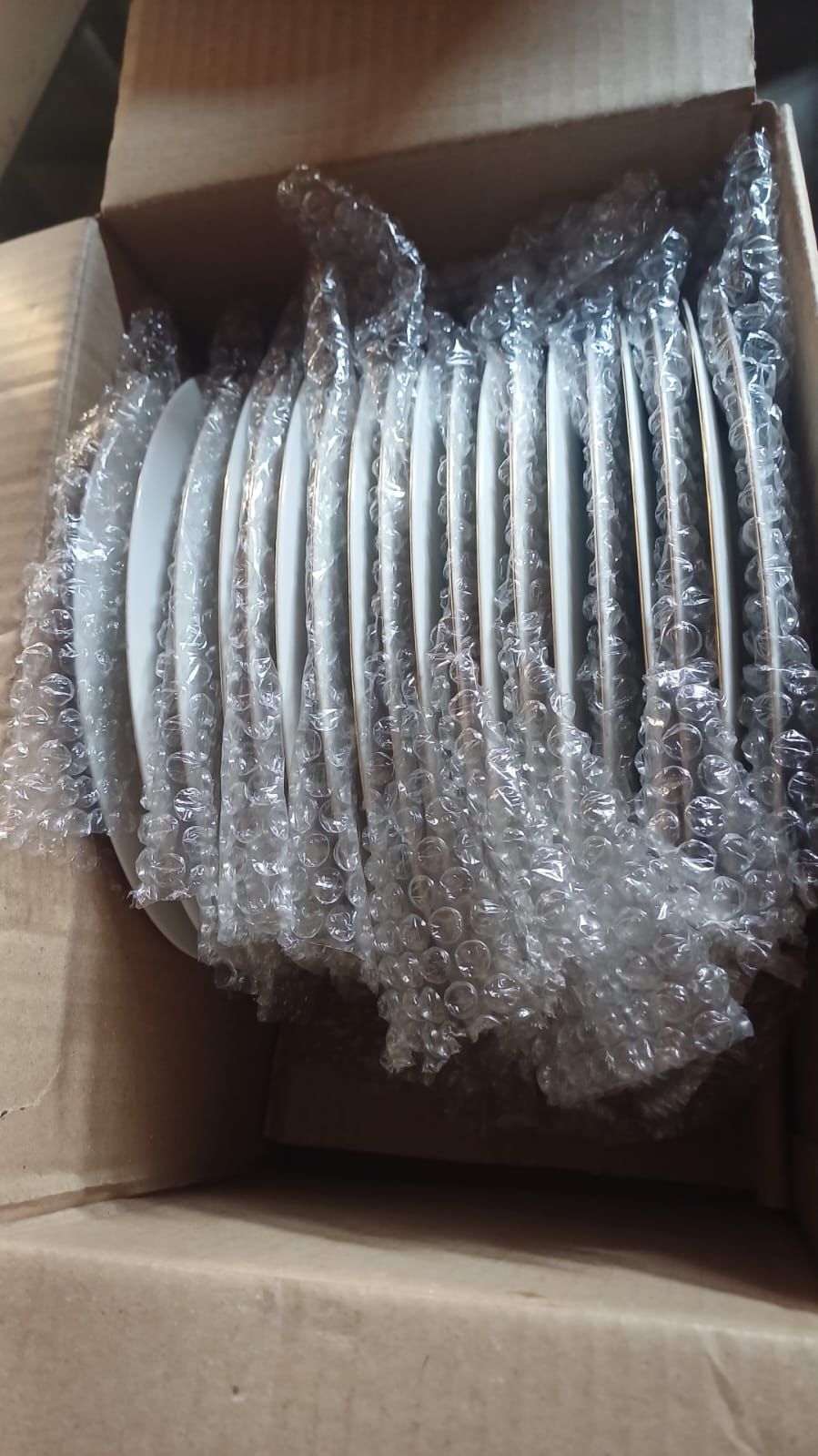 Caja abierta con vajilla y objetos de cocina acomodados y protegidos con material de embalaje