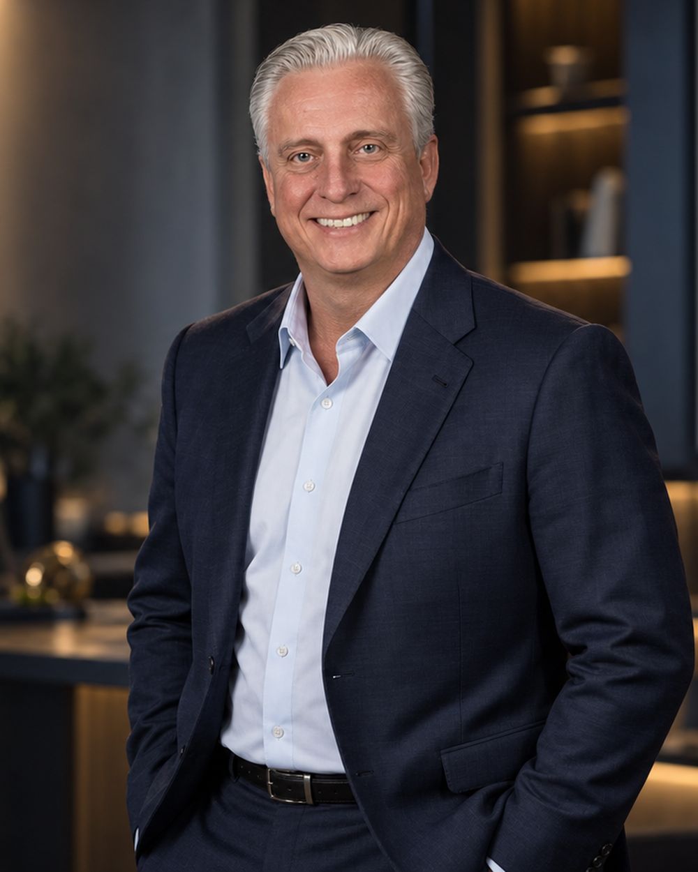 Jim Stocker standing in an executive office in a navy blazer and open-collar shirt