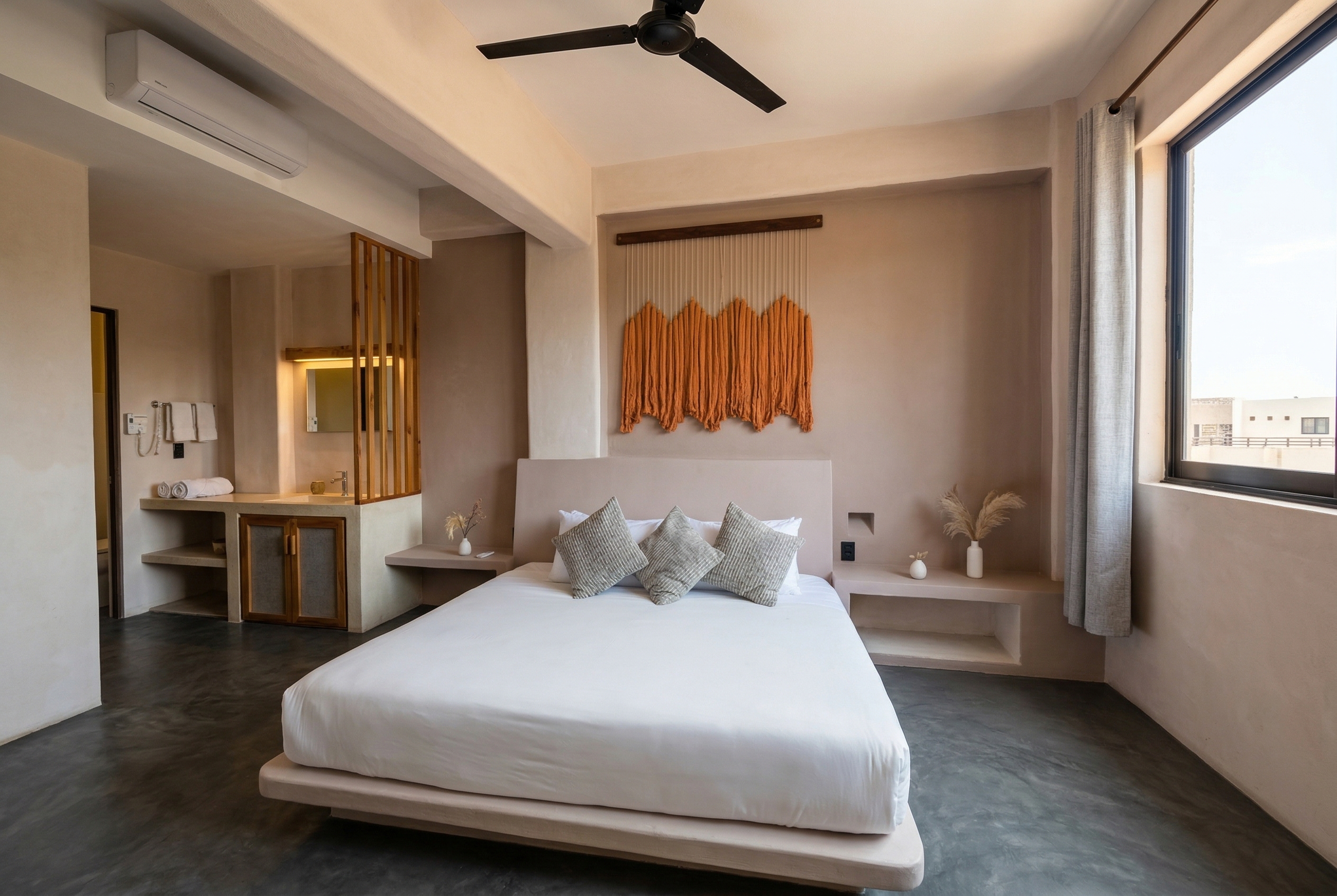 King bed in the Balcony Suite with natural light and macrame wall art