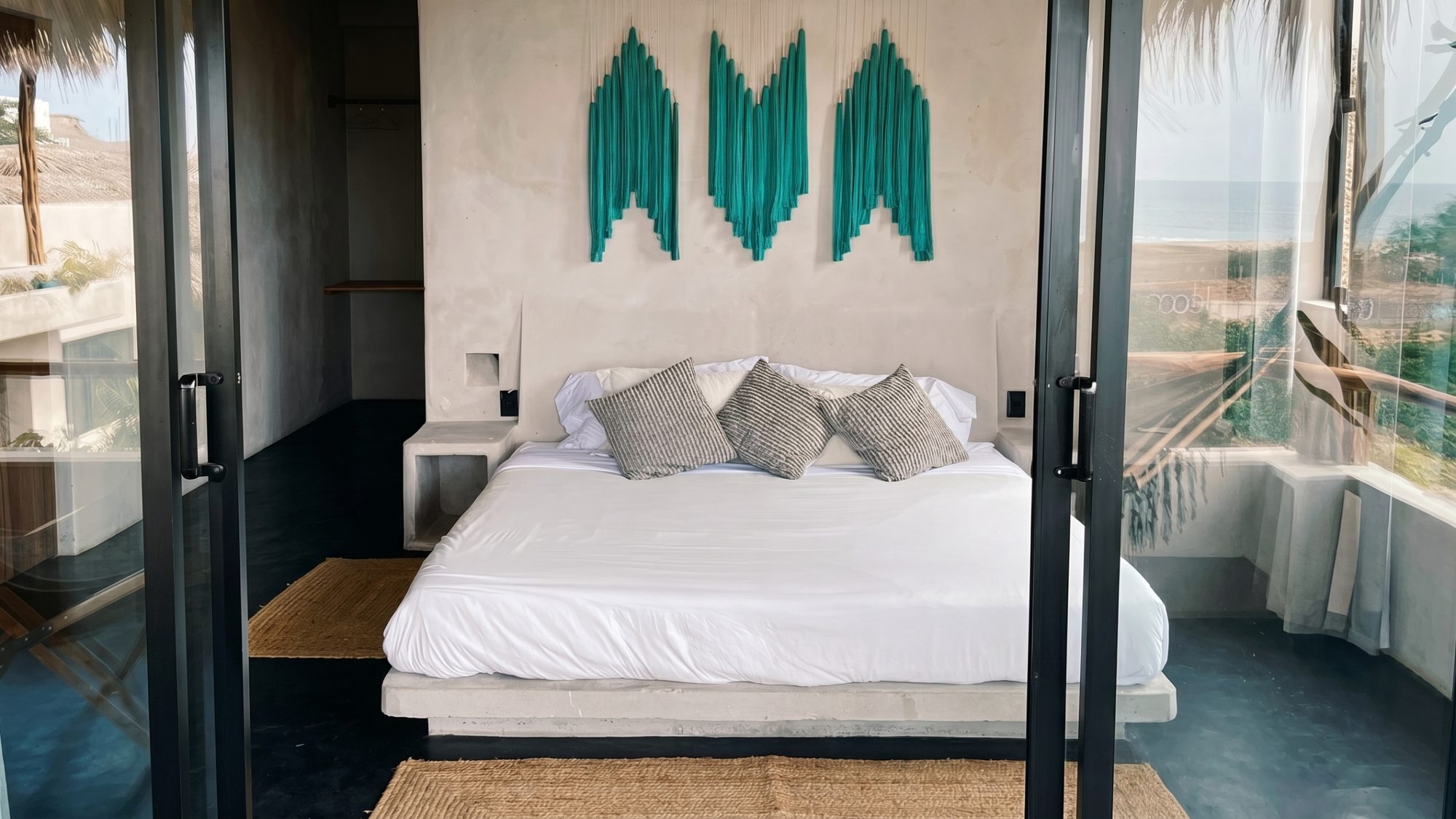 Bedroom with ocean views, turquoise macramé wall art, and a king bed
