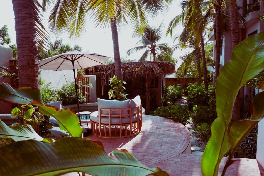 Circular daybed lounge shaded by palm trees in the garden courtyard at Casa Leah