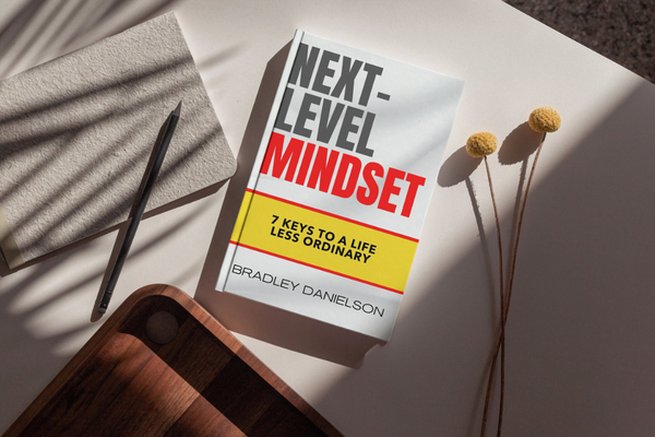 Photo of the book "Next-Level Mindset: 7 Keys to a Life Less Ordinary" sitting on a beautifully arranged desk Photo of the book "Next-Level Mindset: 7 Keys to a Life Less Ordinary" sitting on a beautifully arranged desk