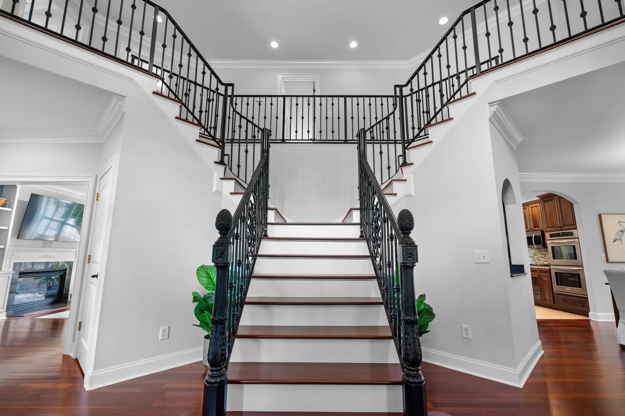 Staircase with black metal railings and wooden steps overlooking a kitchen