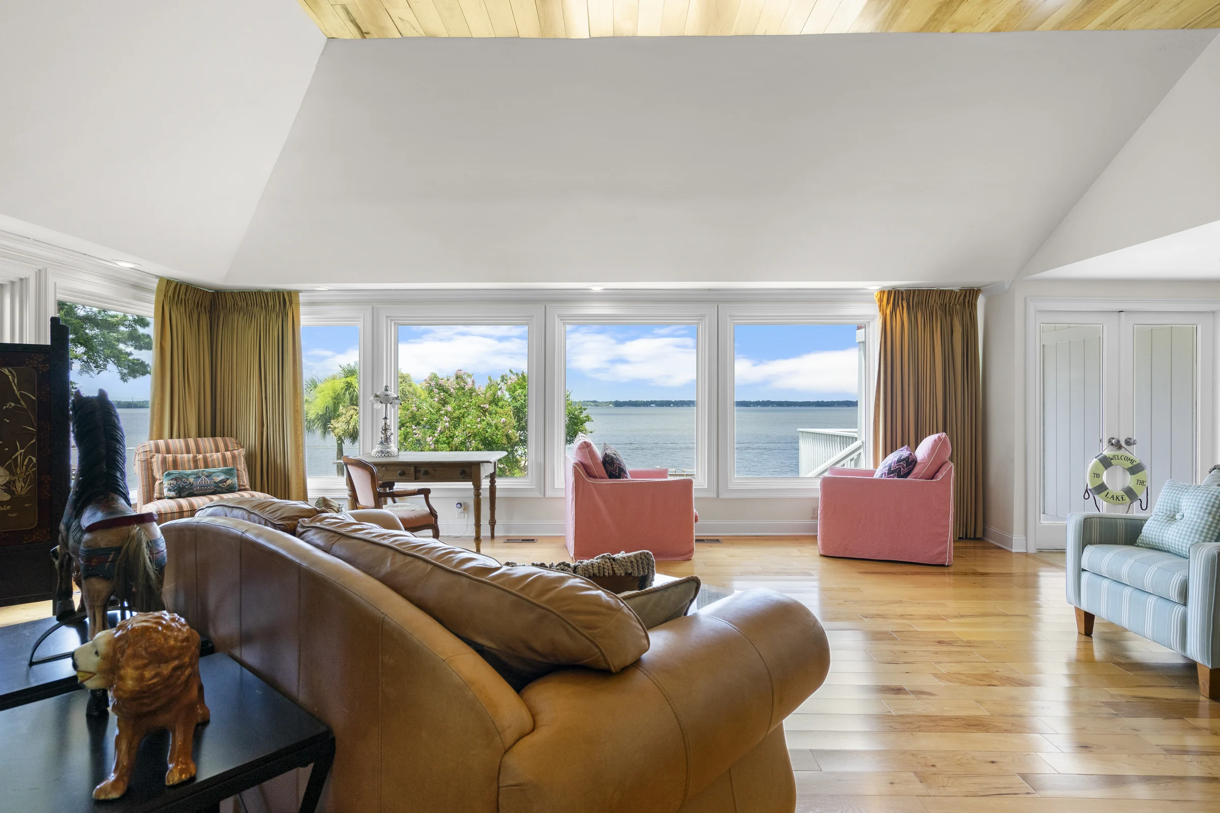 Living room with a large window overlooking the lake, with armchairs and a desk