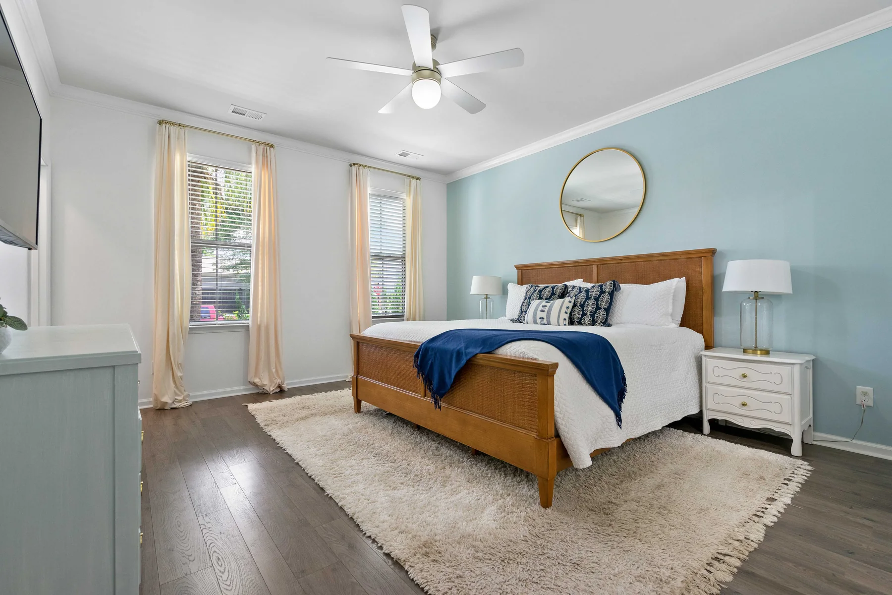 Bedroom with a wooden bed, white bedding, a blue throw, and a ceiling fan