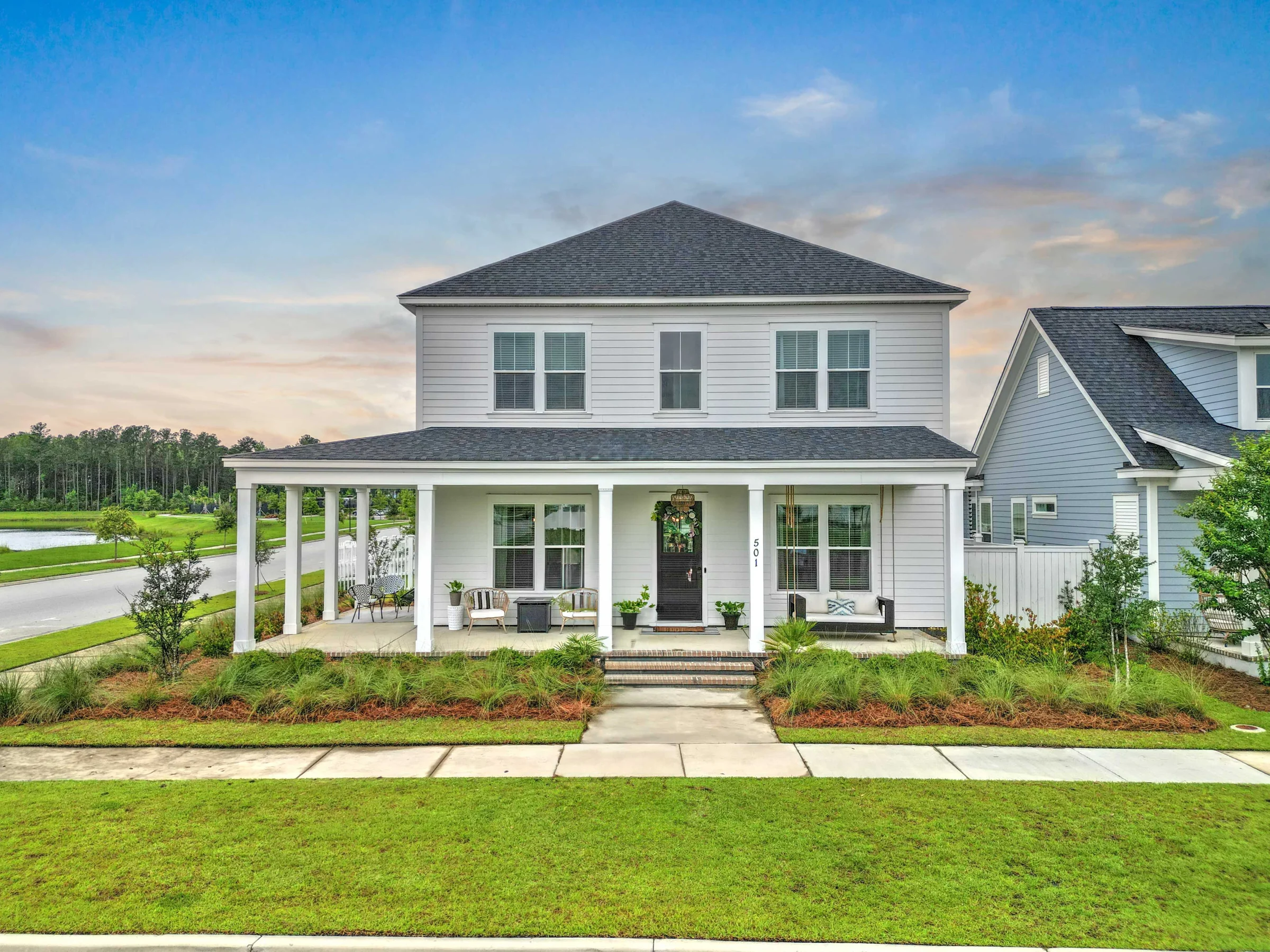 Two-story white home with a front porch, black roof, and large windows
