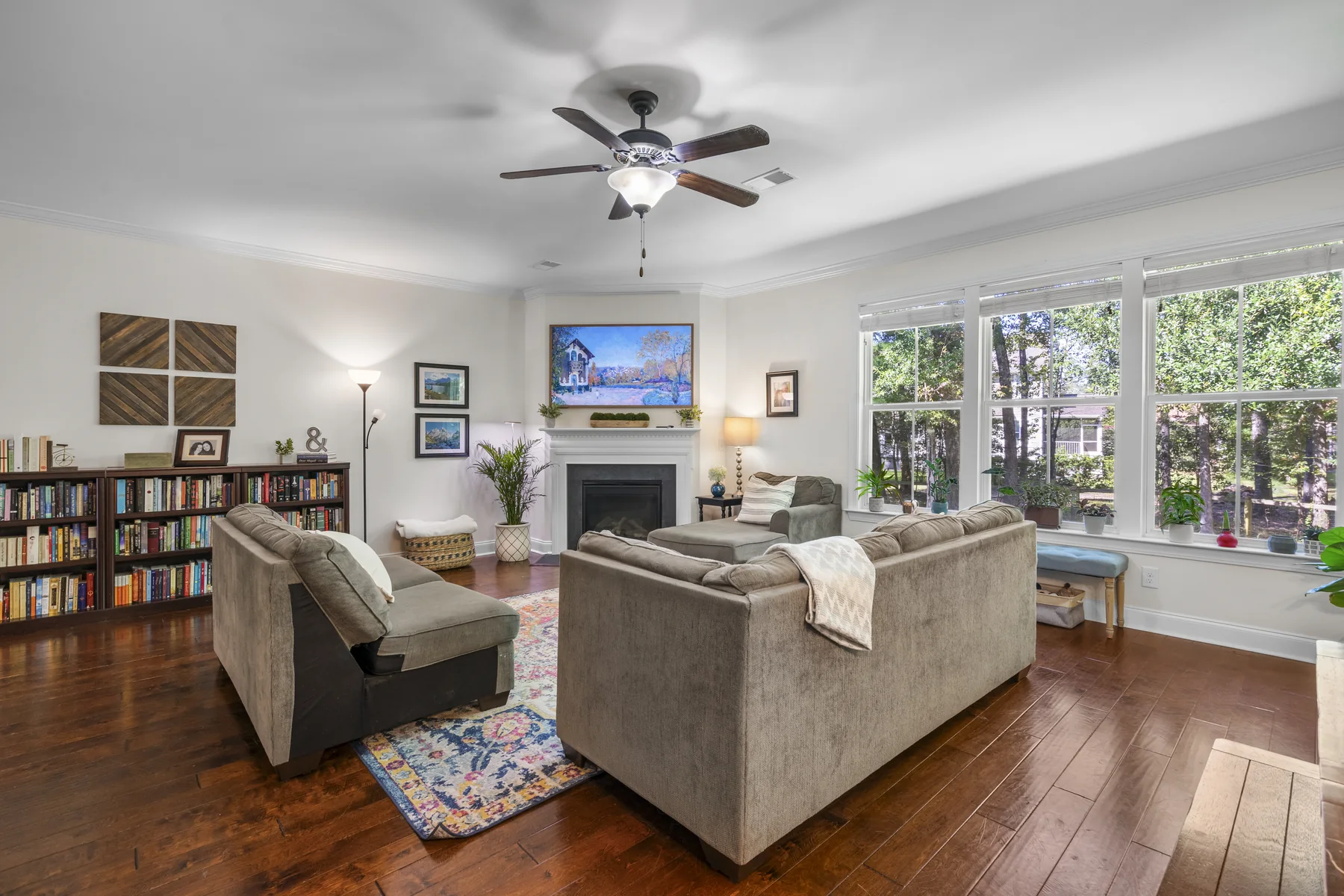 Living room with a fireplace, couches, bookshelf, and framed art