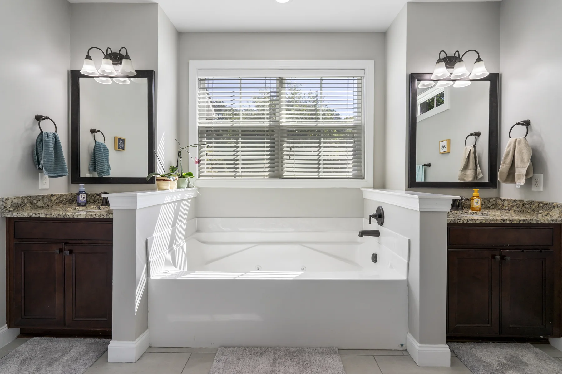 Primary bathroom with dual vanities, a soaking tub, and natural light from the windows