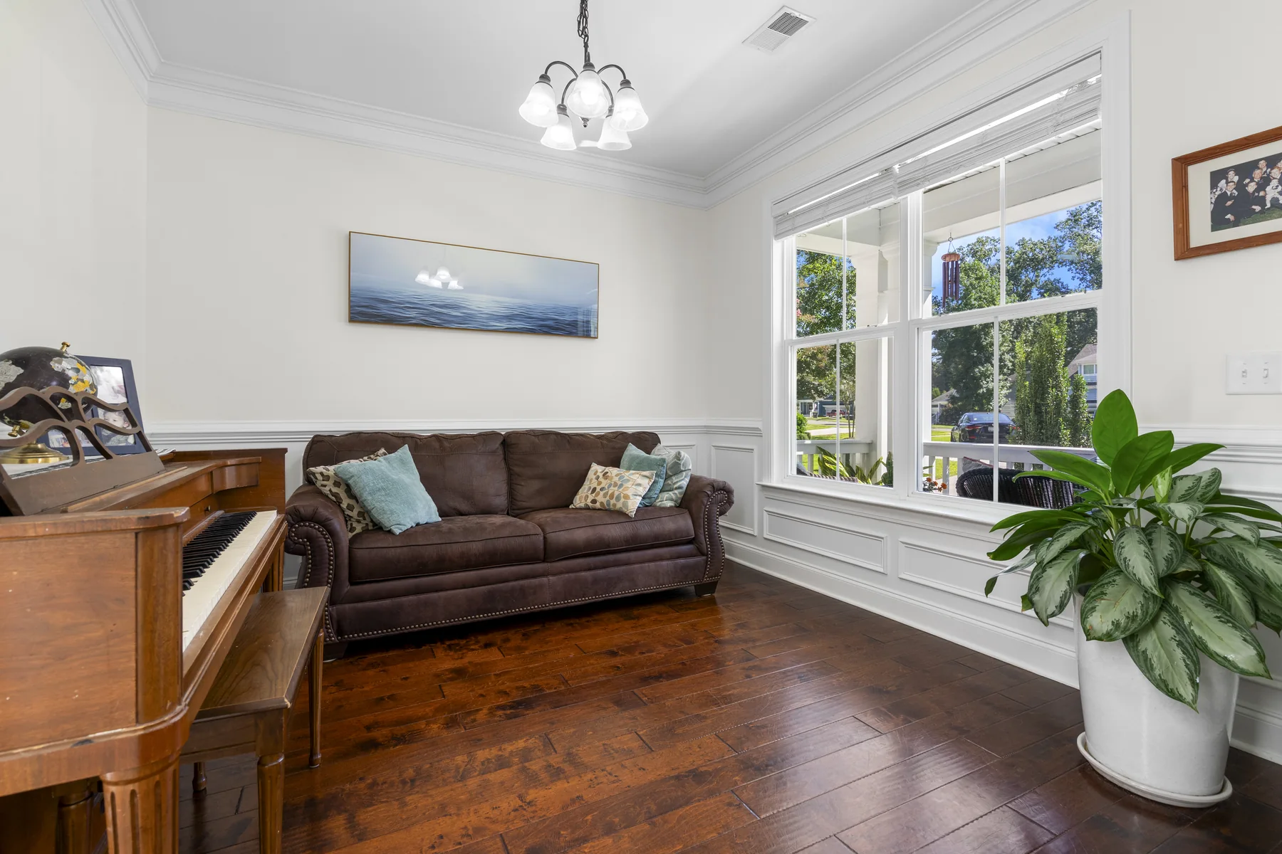 Bright room with a piano, a large window, and a plant in the corner