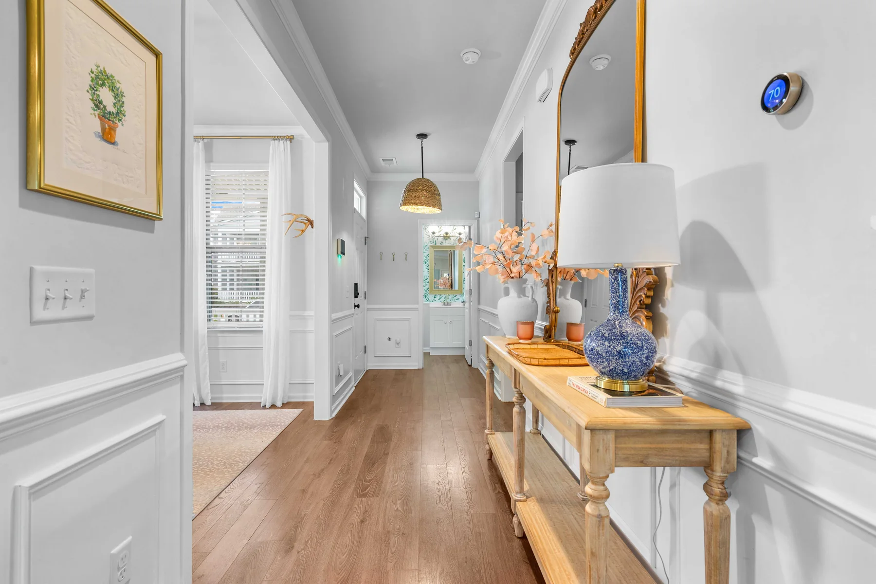 Decorated hallway with a wall mirror, framed art, and a table with flowers