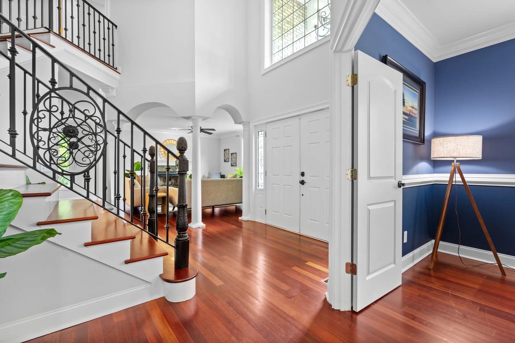 Interior staircase with a decorative metal railing, hardwood floors, and blue walls
