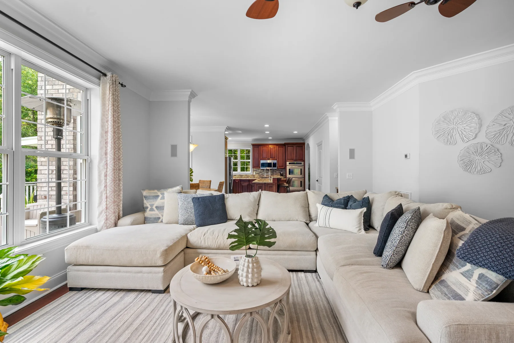 Living room with a large sectional sofa, coffee table, and kitchen in the background