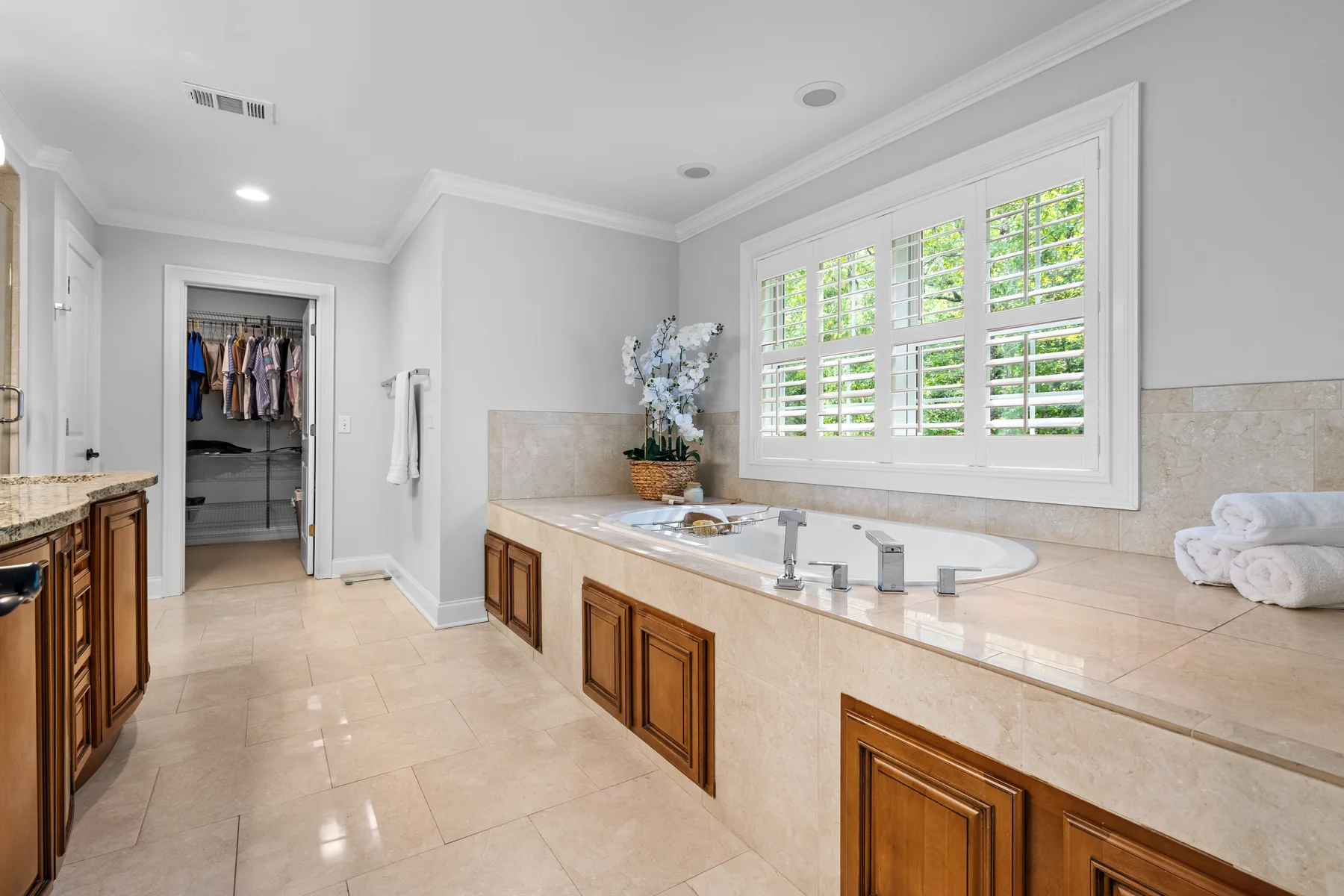 Bathroom with a large window, a bathtub, and a closet
